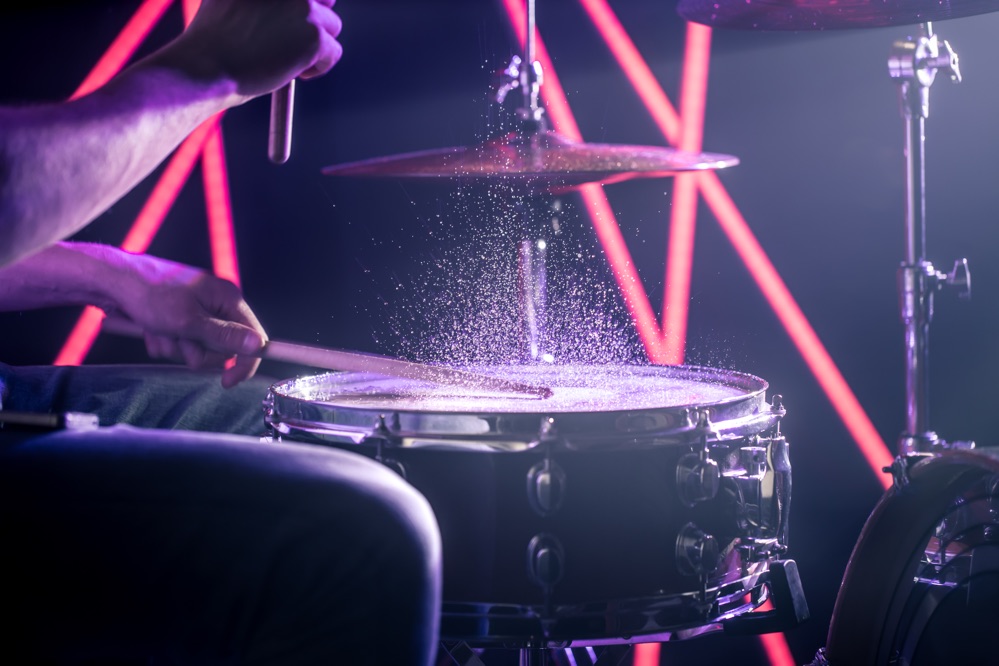 Tribus Bar: man-plays-drums-background-colored-lights